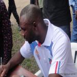 Le sélectionneur de l?équipe nationale de football, Florent Ibenge, en train de signer dans le livre d?or du collège Boboto jeudi 24 mars 2016. Photo Fecofa/ Angengwa Agbeme.